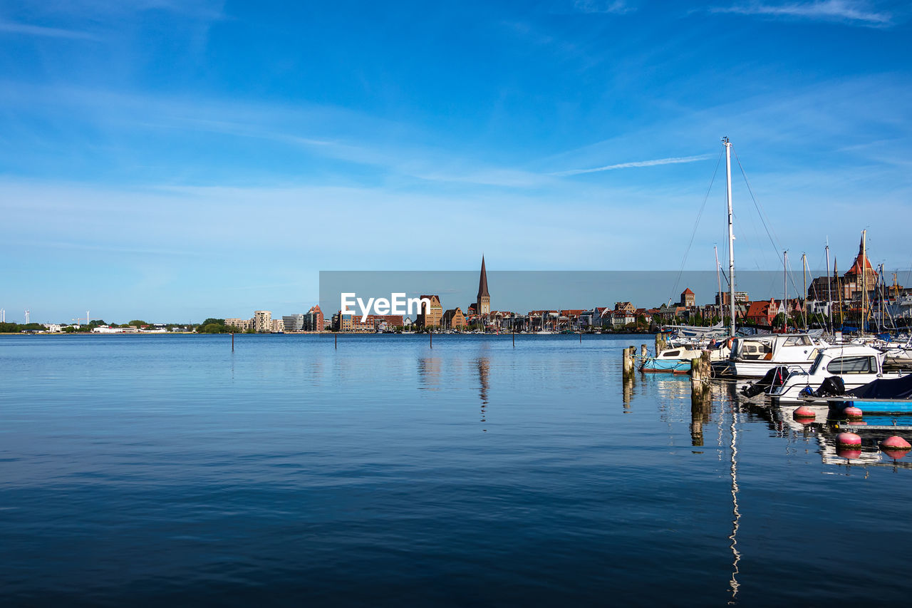 SAILBOATS MOORED IN CITY AGAINST SKY