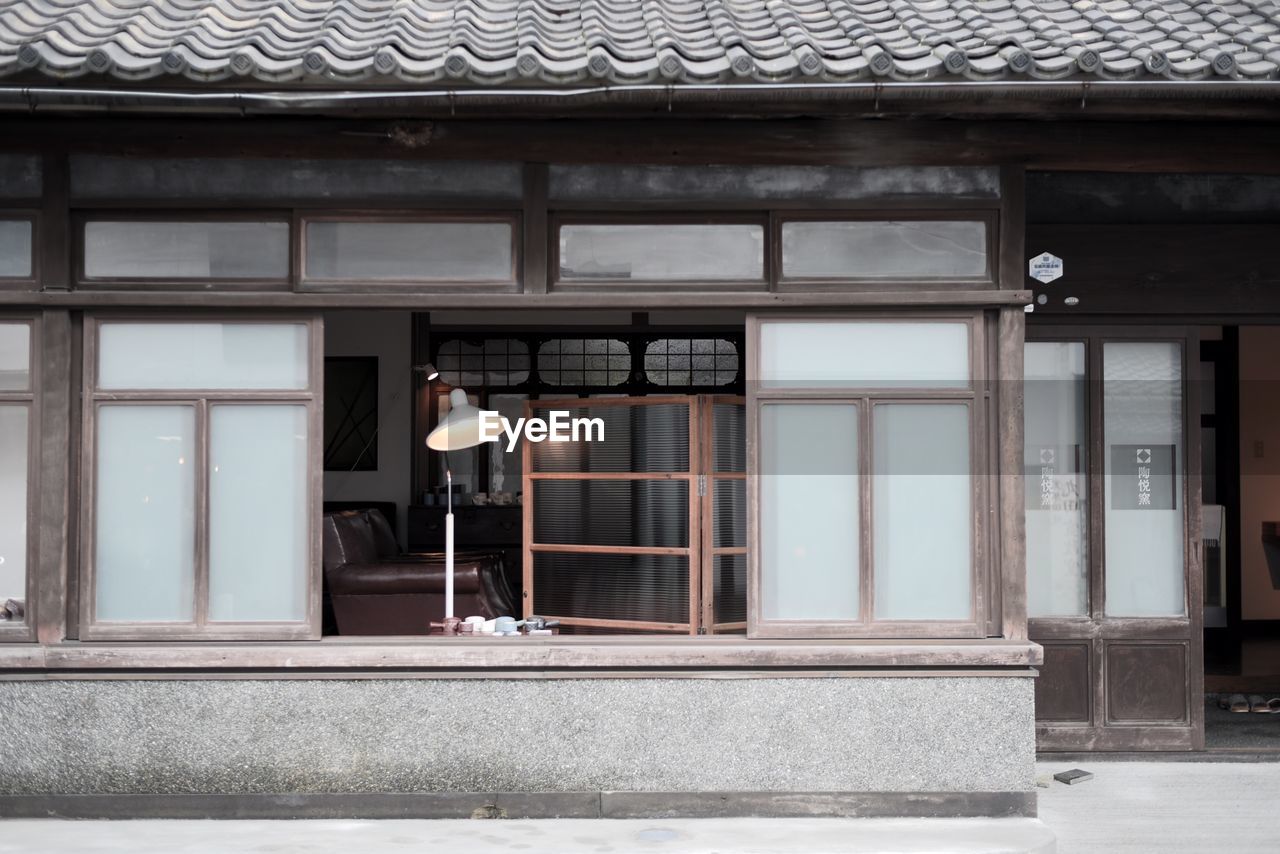 REAR VIEW OF MAN WALKING ON STREET AGAINST BUILDINGS