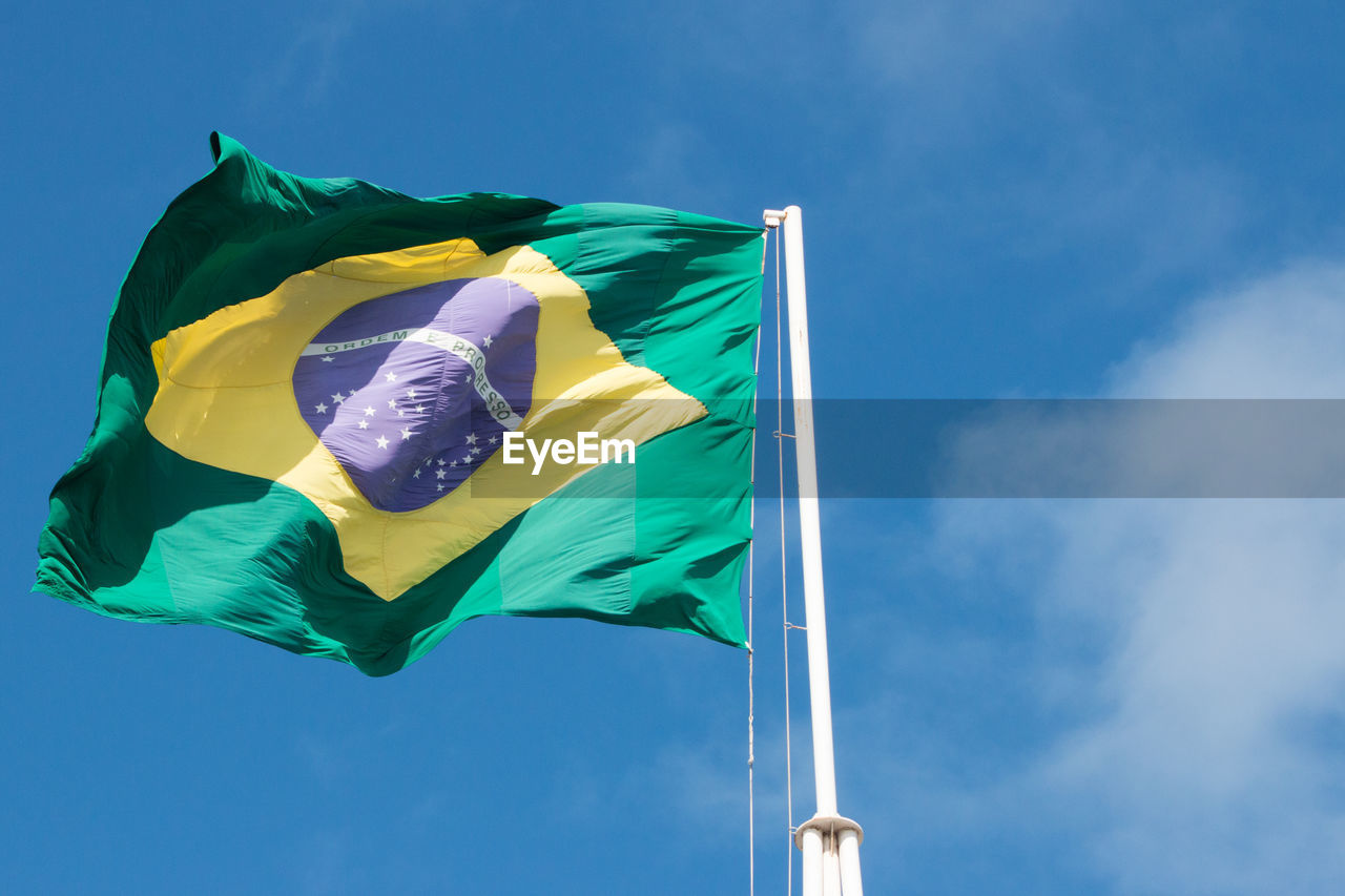 Low angle view of brazilian flag against blue sky