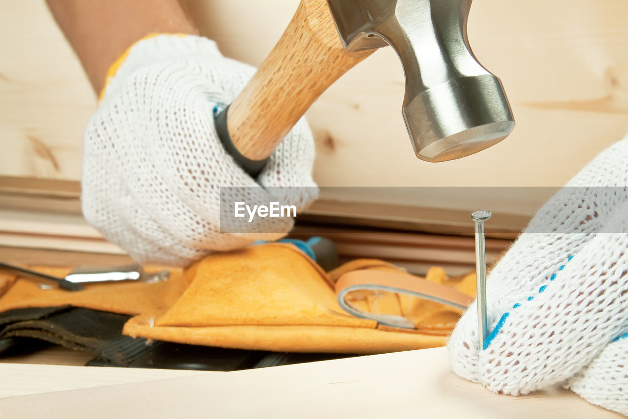 Close-up of craftsperson hammering nail at workshop