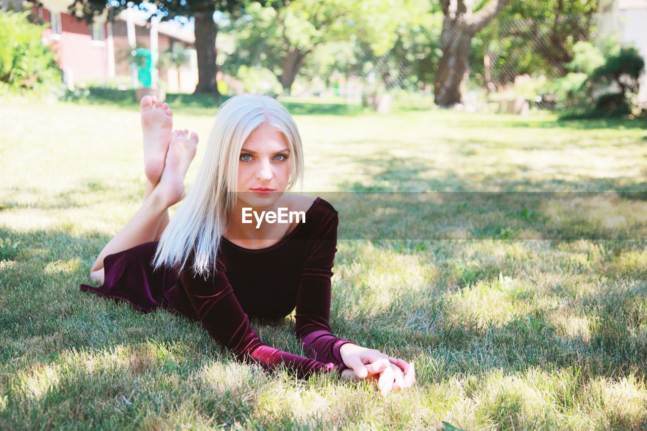 Portrait of beautiful woman lying on grassy field at park