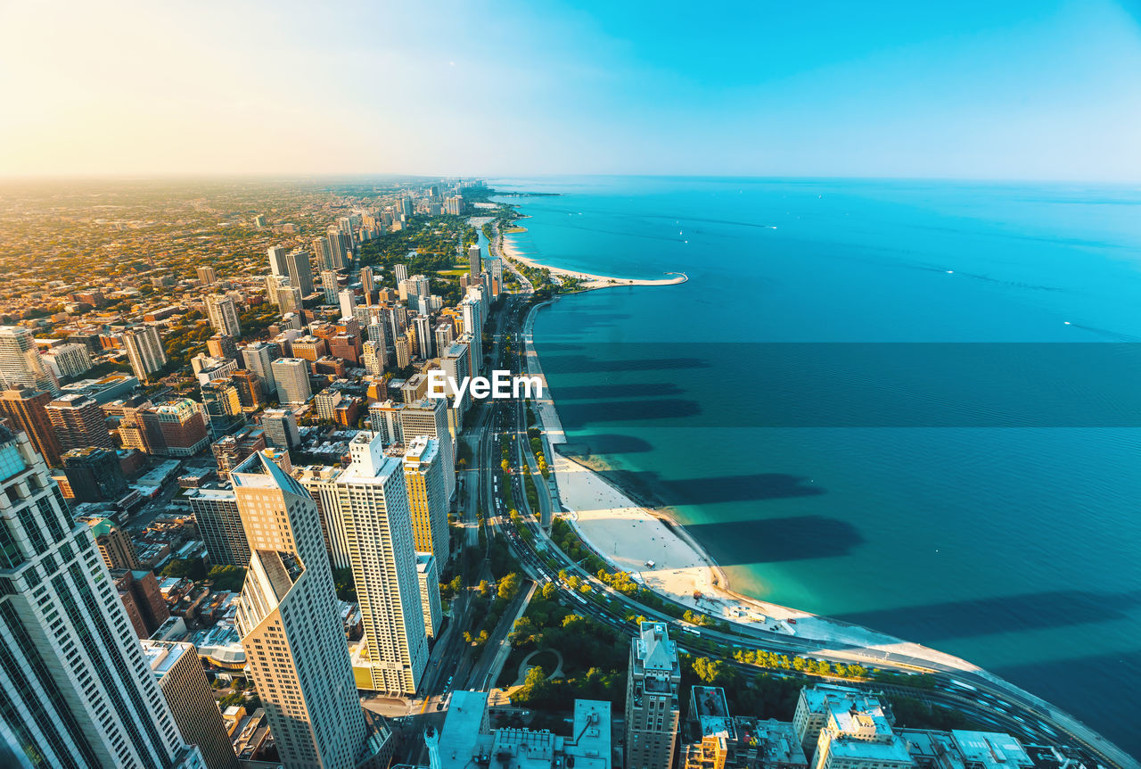 Cityscape and sea against blue sky during sunset