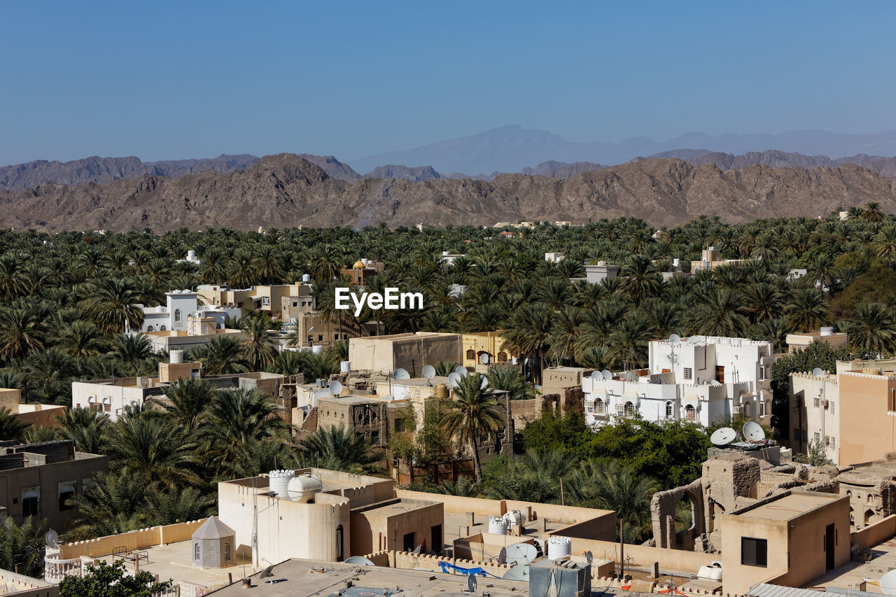 High angle view of buildings and palm trees with mountains against sky