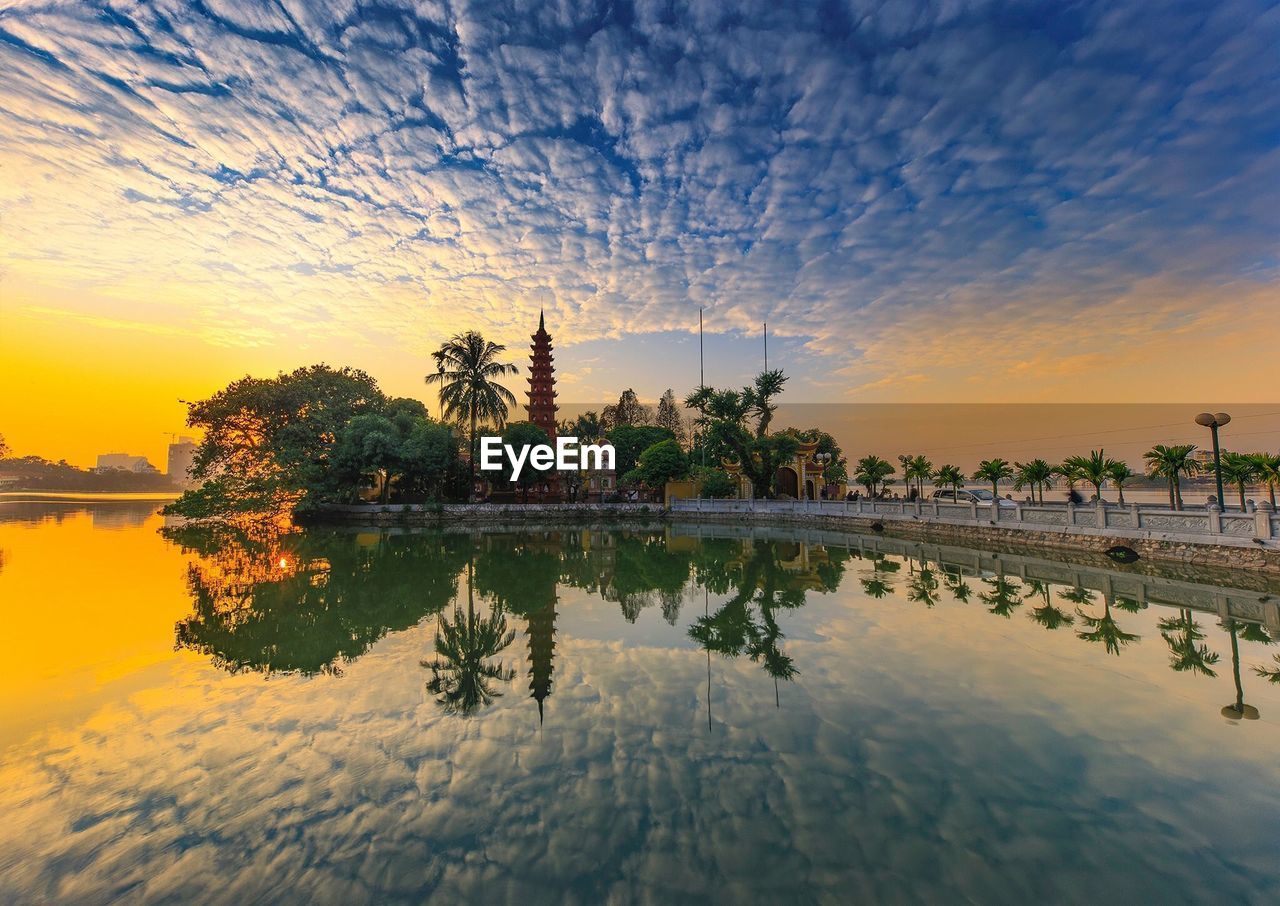 Reflection of trees in lake against cloudy sky