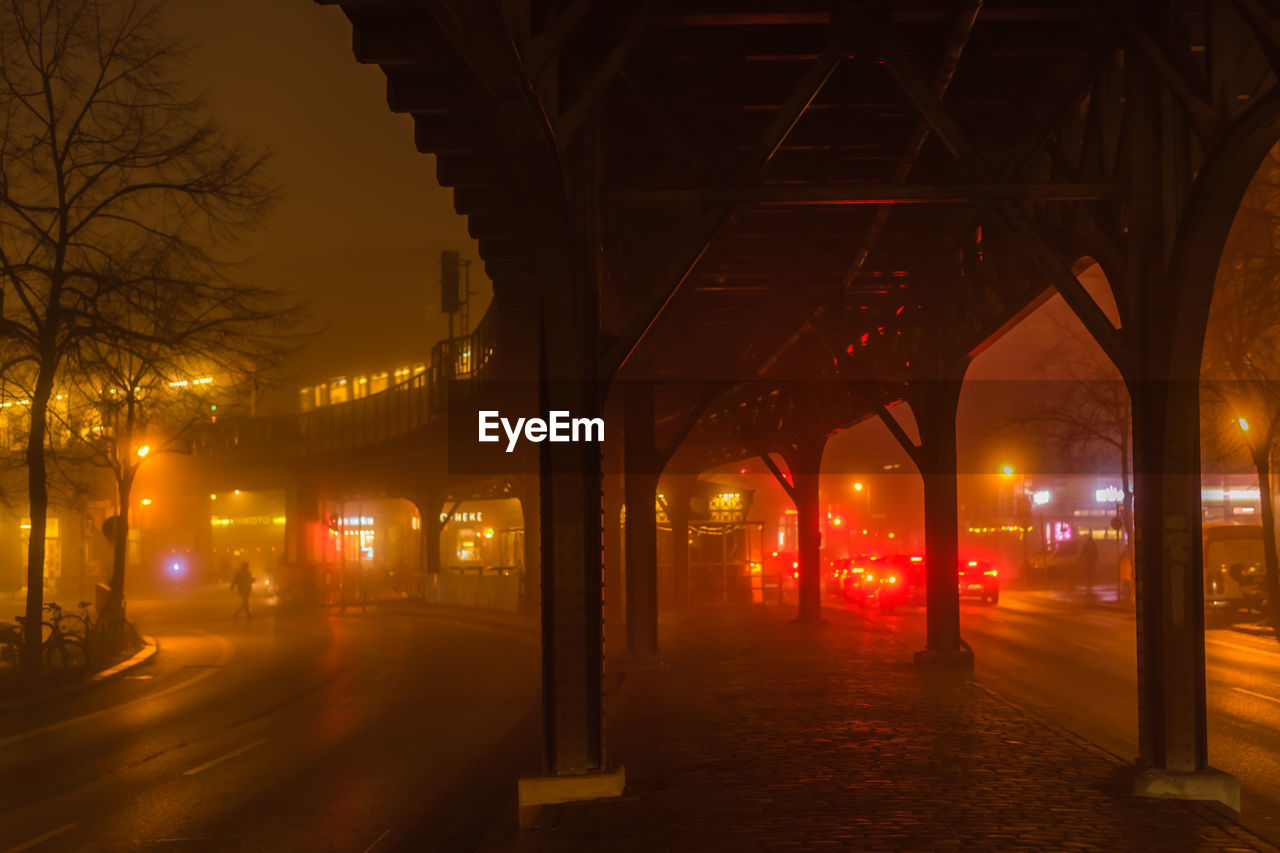 Bridge over illuminated street in city at night