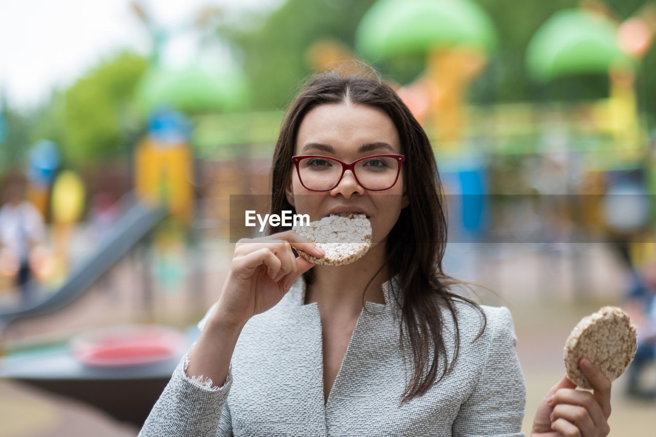 PORTRAIT OF SMILING YOUNG WOMAN EATING ICE CREAM