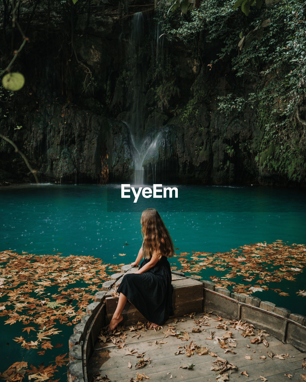 Woman sitting on boat by waterfall