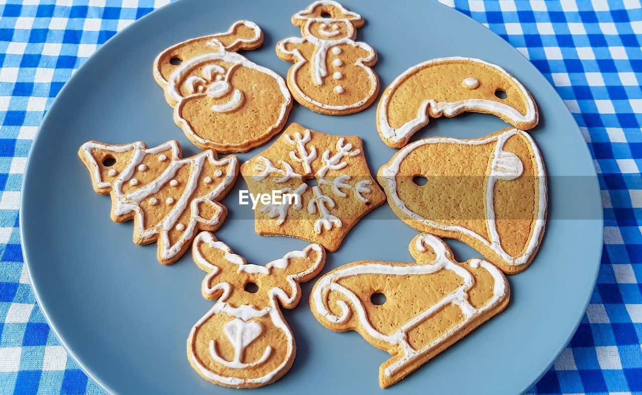 High angle view of gingerbread cookies in plate on tablecloth