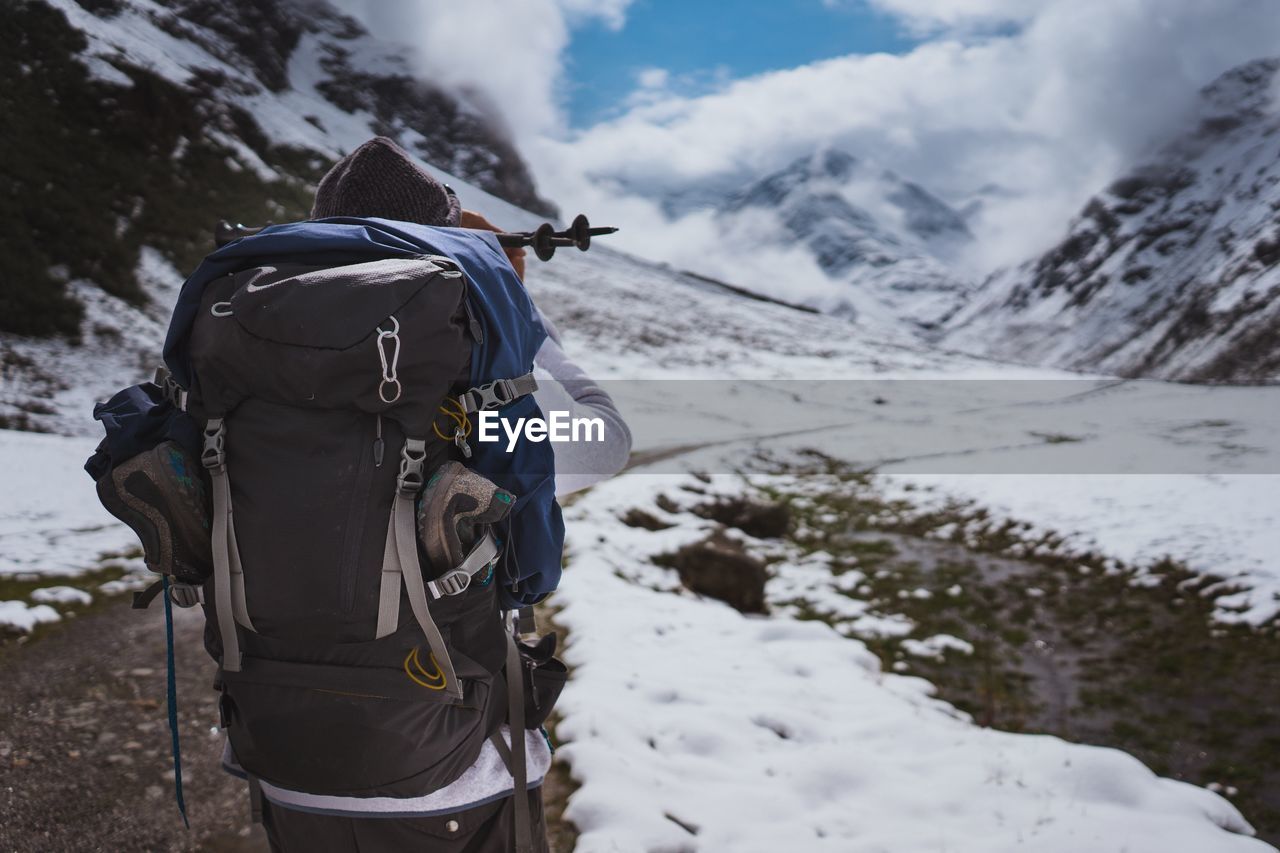 Rear view of male hiker hiking on snowcapped mountain