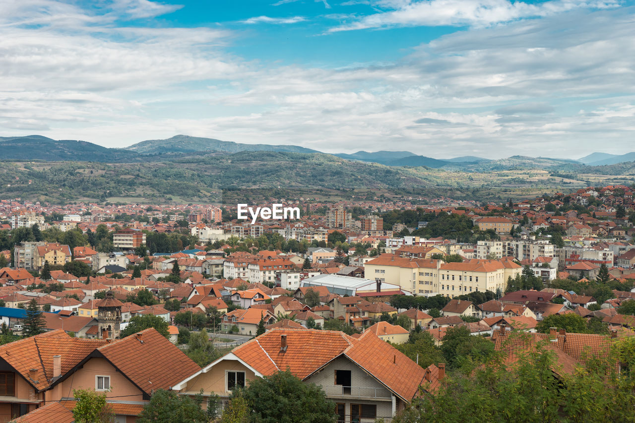 Aerial view of townscape by mountains against sky