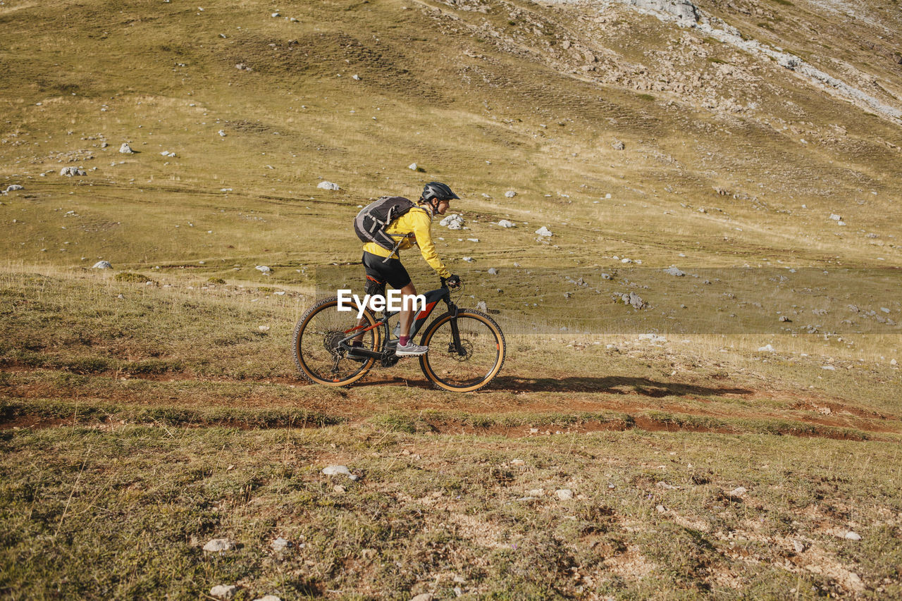 Mid adult woman riding electric bicycle on mountain at somiedo natural park, spain