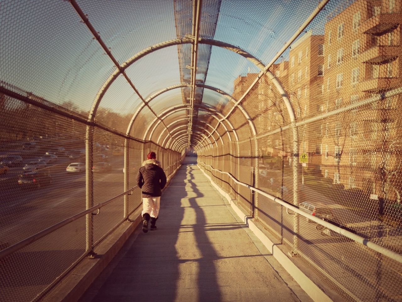 Rear view of person walking on covered overpass