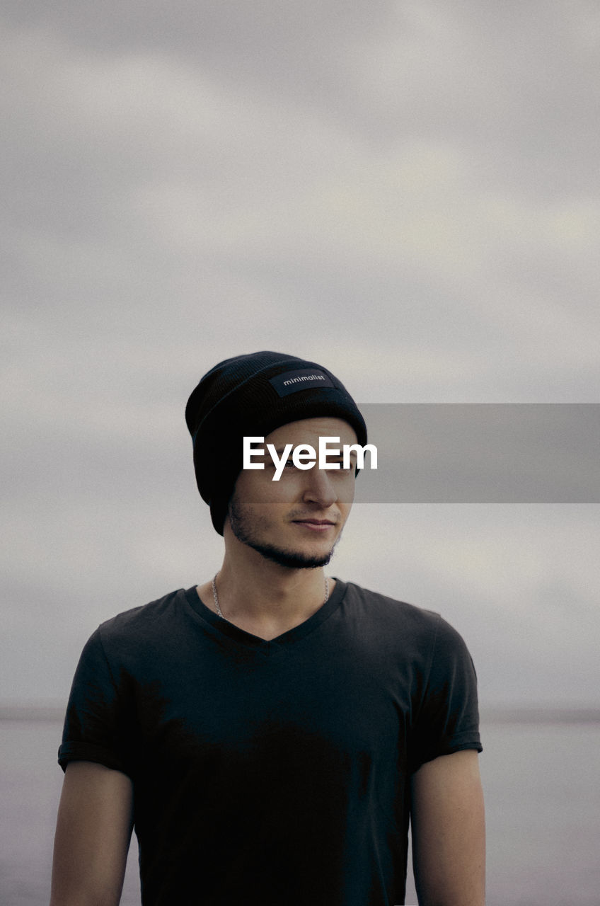 PORTRAIT OF YOUNG MAN LOOKING AGAINST SKY