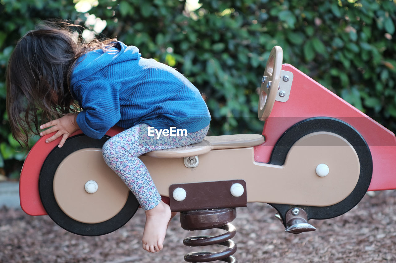 Side view of girl sitting on spring ride at park