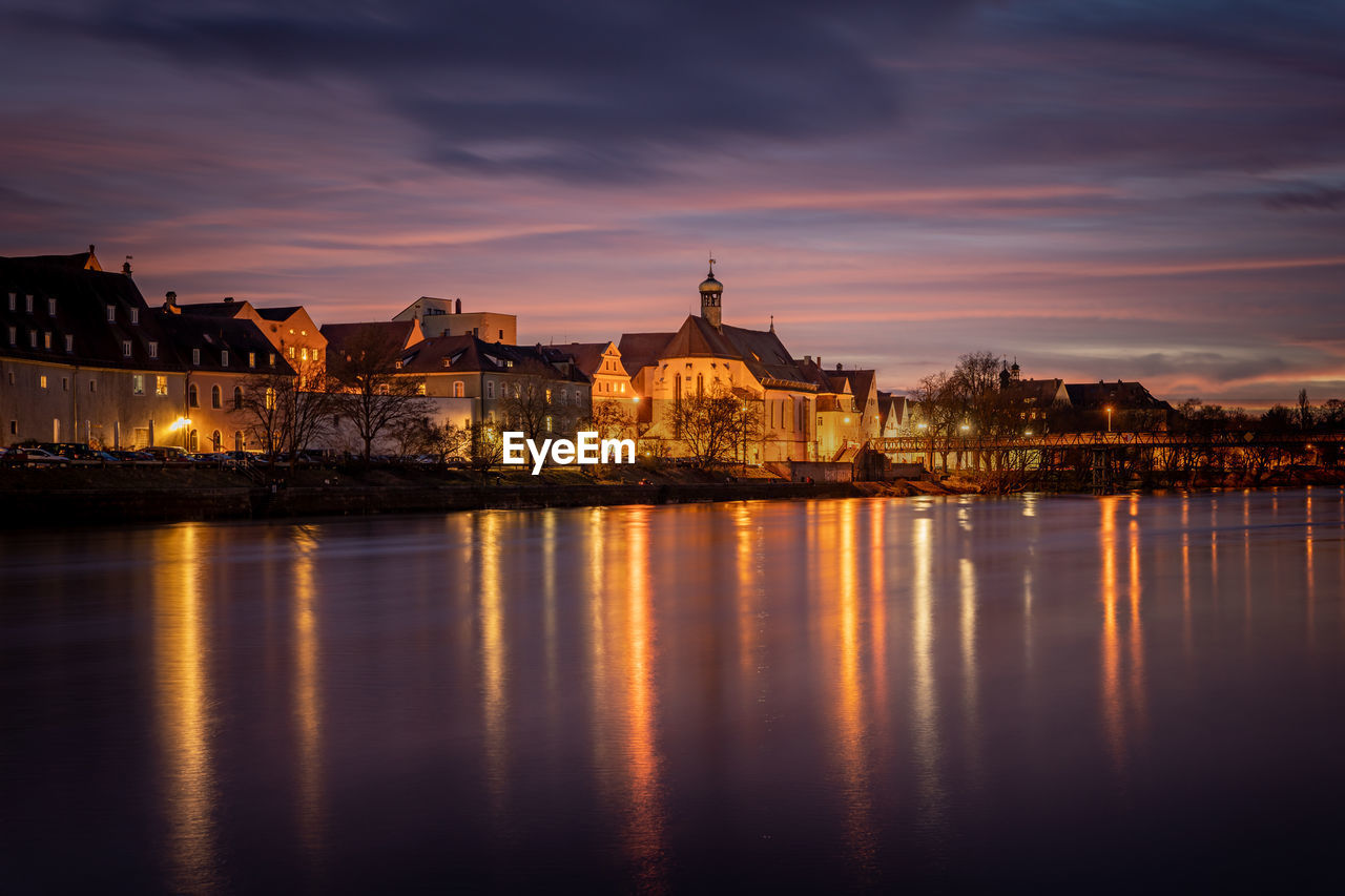 Reflection of illuminated buildings in city at sunset