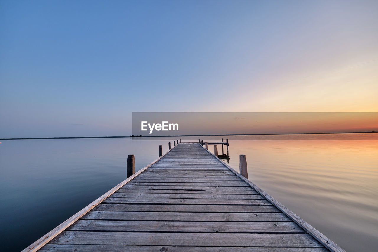 Pier over sea against sky during sunset