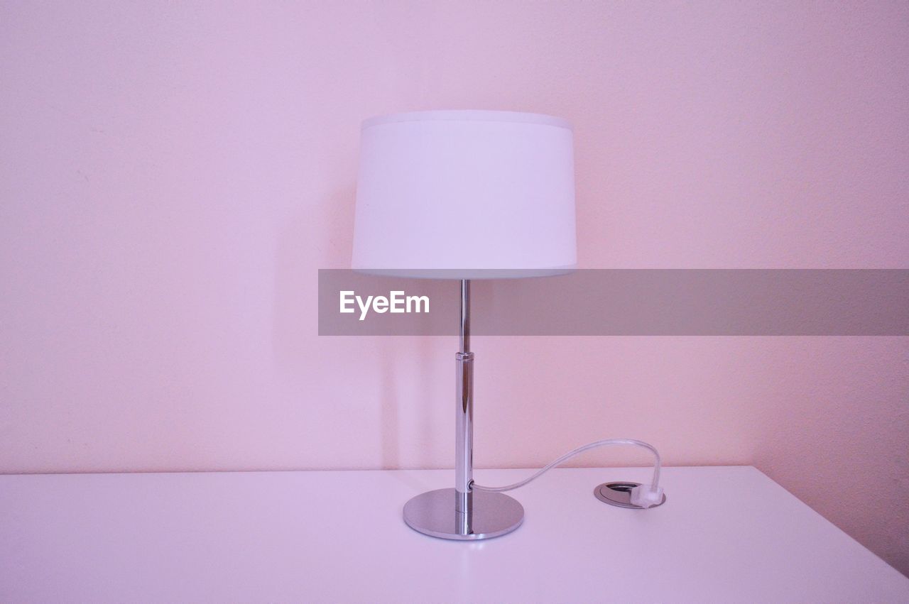Lamp on table by wall