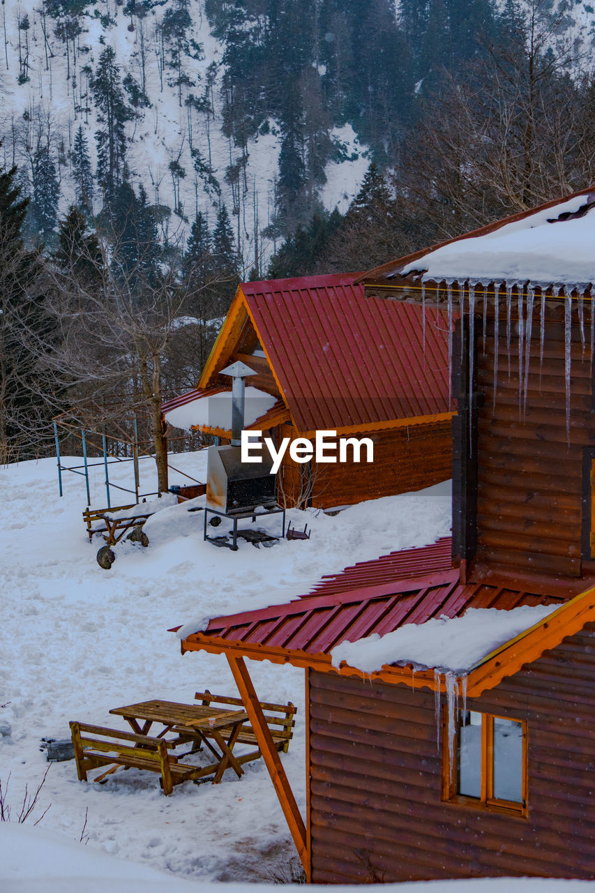 House on snow covered field by building during winter