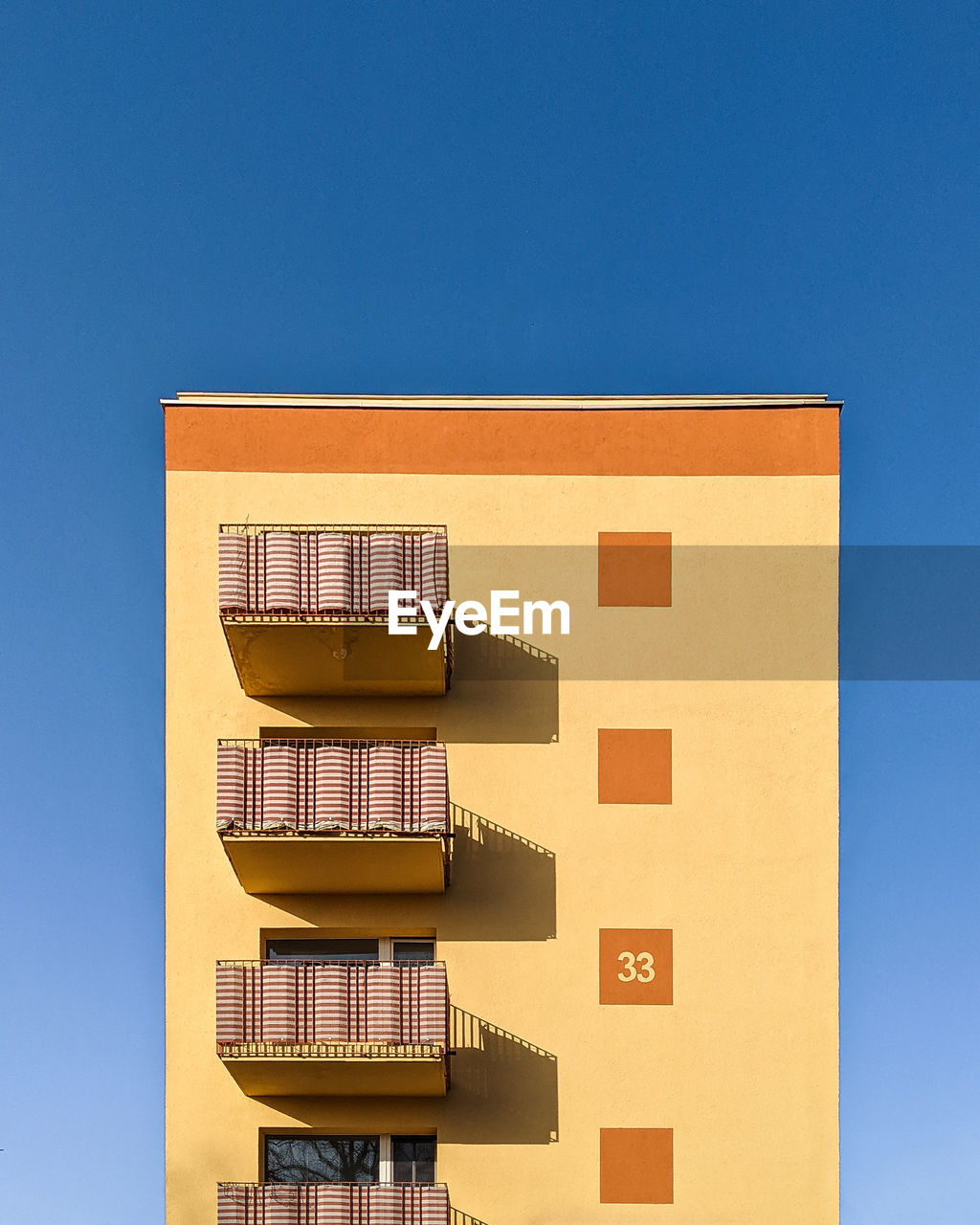 Low angle view of yellow building against clear blue sky