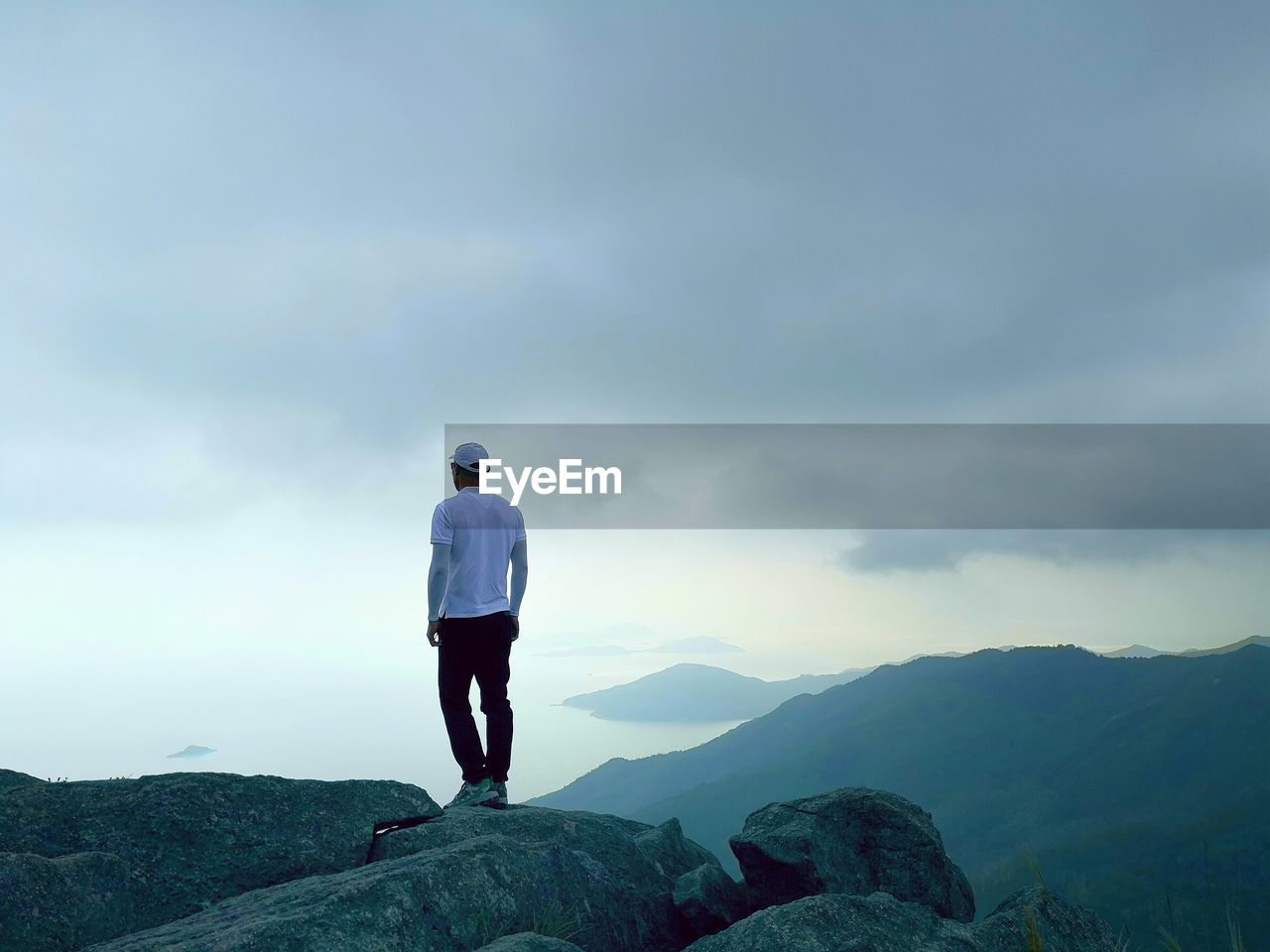 Rear view of man standing on mountain against sky