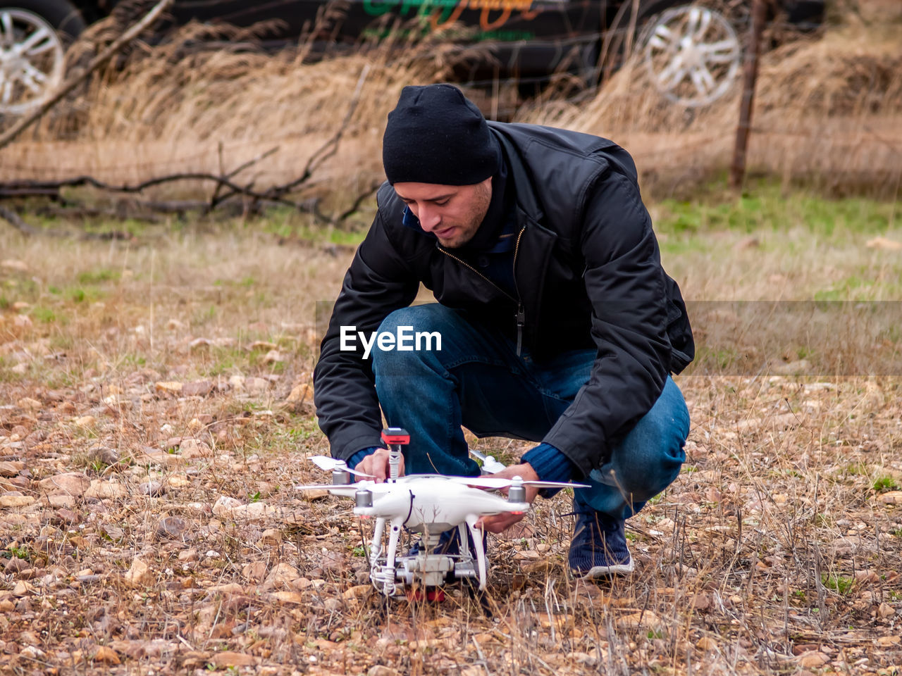 Man crouching by drone on grass