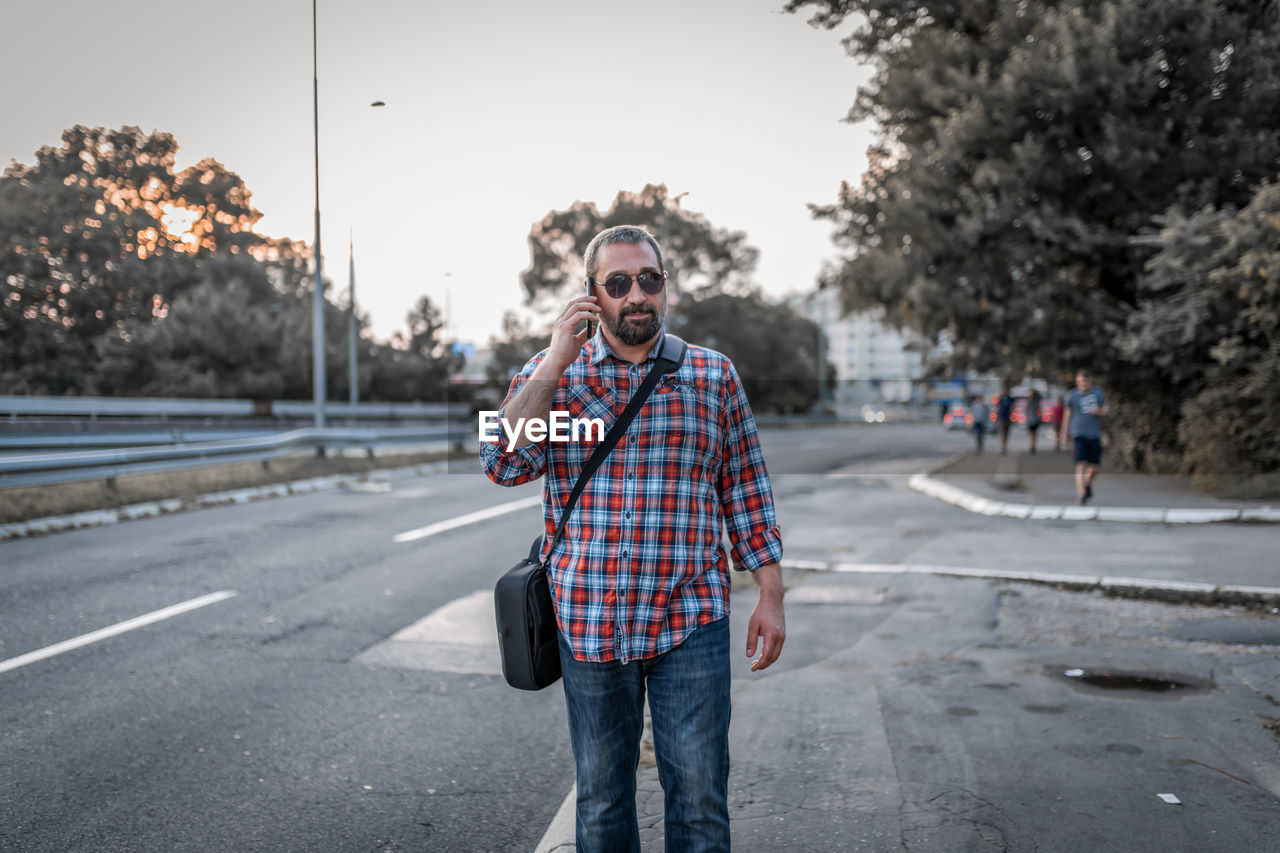 Portrait of handsome businessman with sunglasses and plaid shirt . he talks over his mobile phone