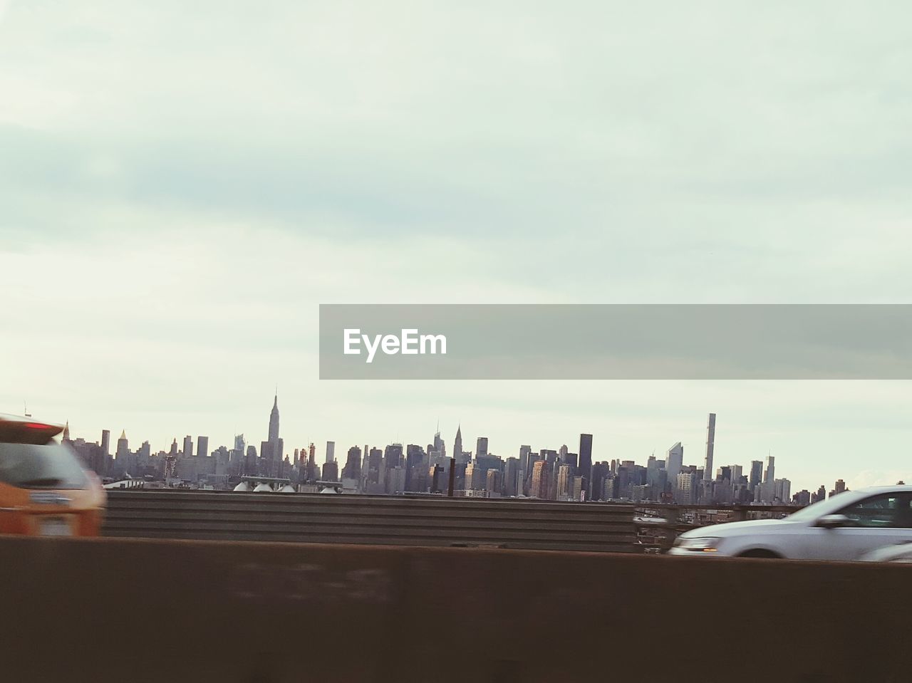 Cityscape against cloudy sky seen from road