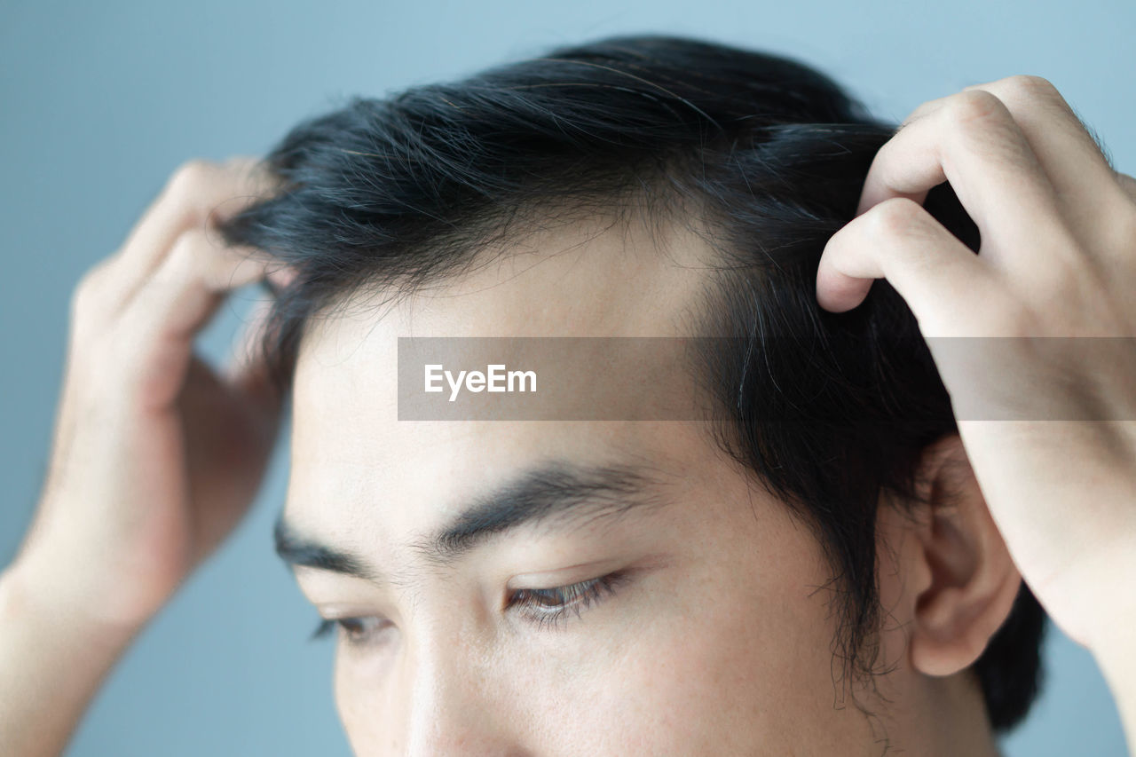 Close-up of young man touching his hair