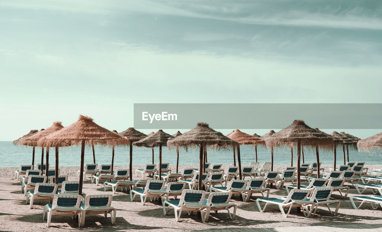 Lounge chairs on beach against sky