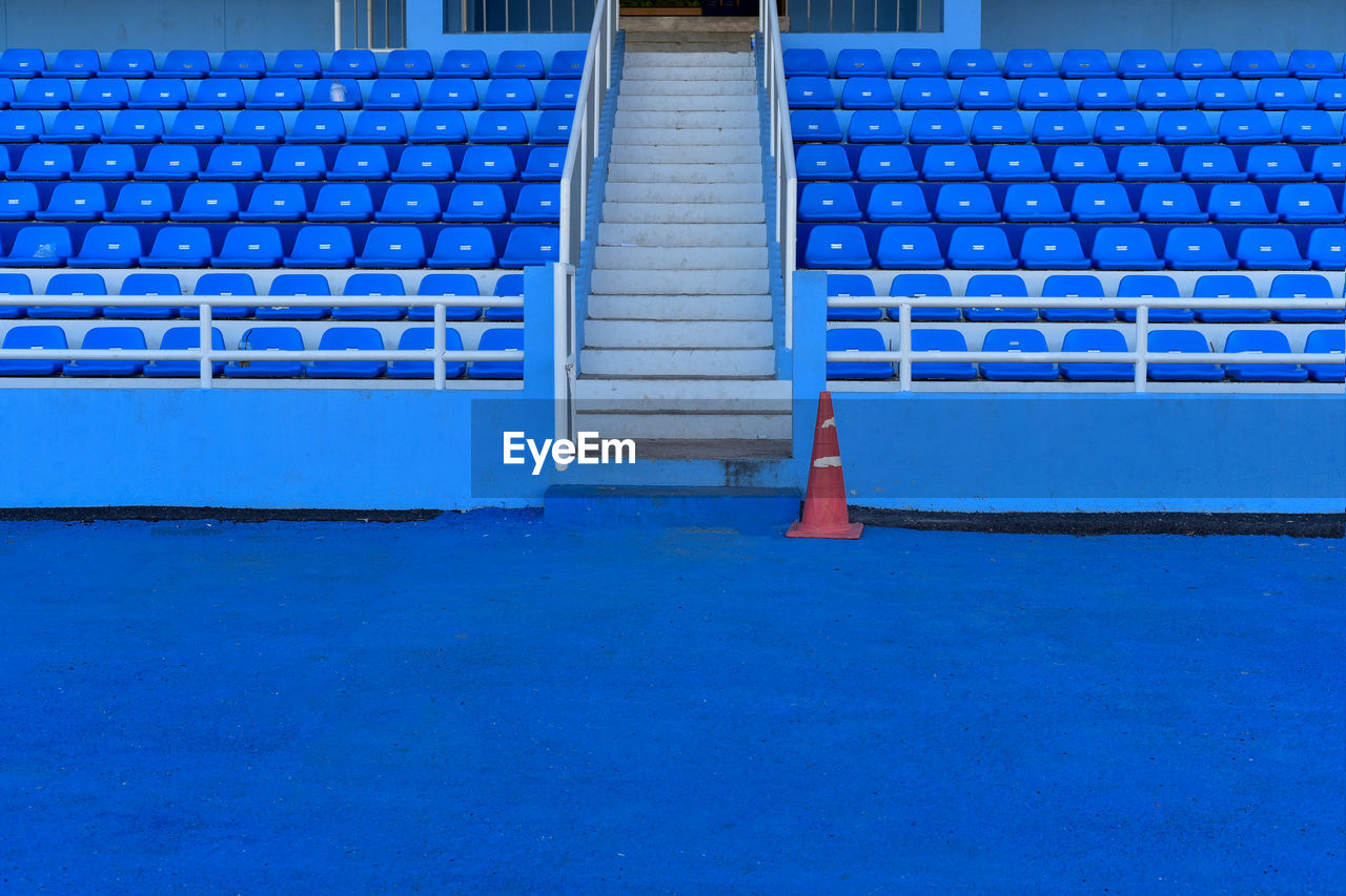 EMPTY CHAIRS BY SWIMMING POOL AGAINST WALL