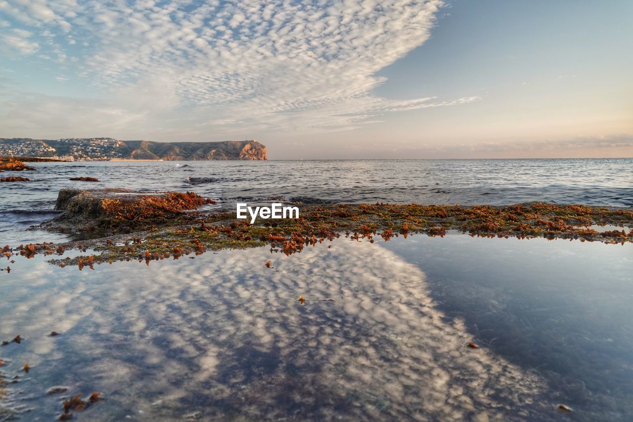 SCENIC VIEW OF ROCKS ON BEACH AGAINST SKY