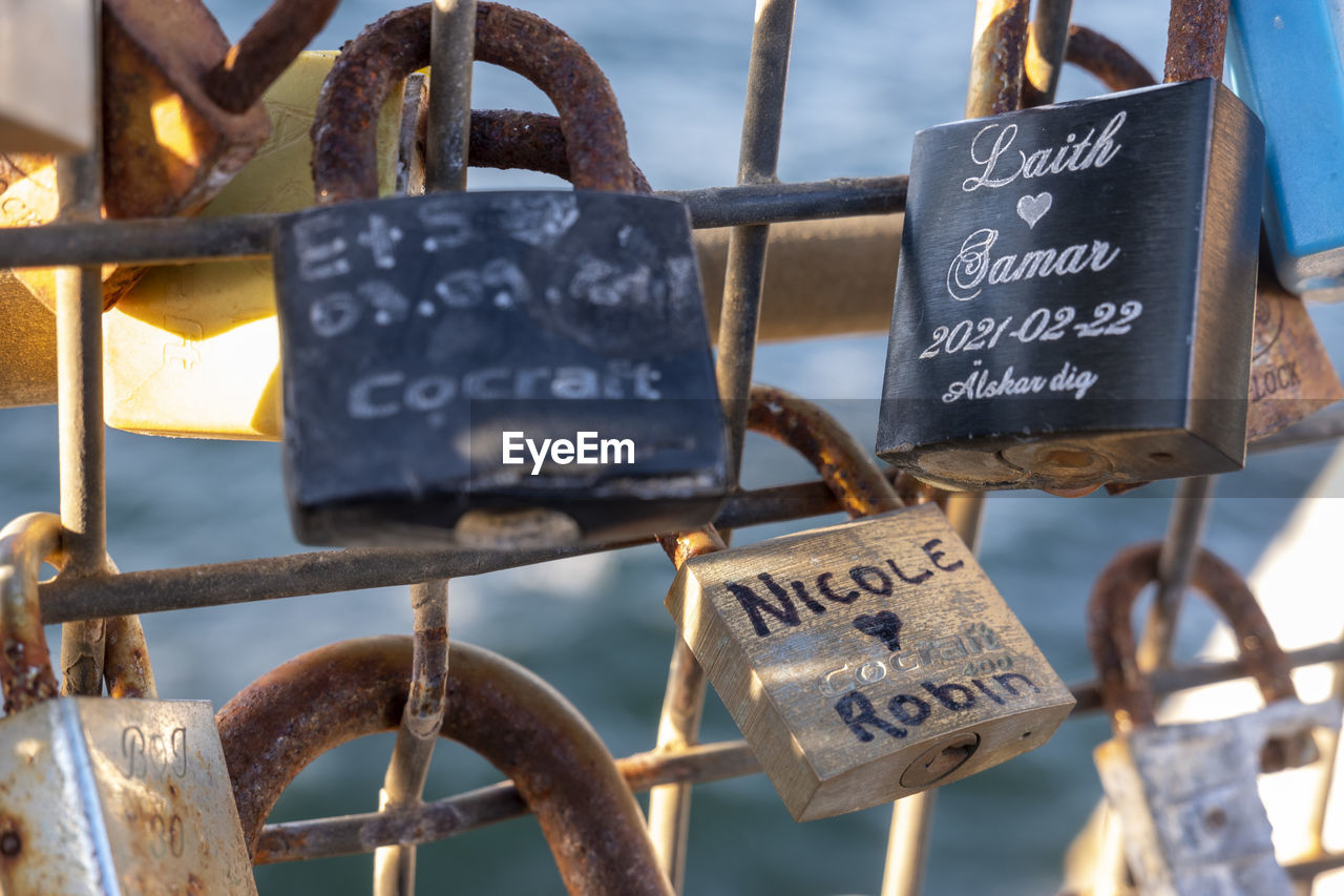 padlock, lock, love, positive emotion, text, hanging, metal, emotion, communication, love lock, iron, hope, protection, security, no people, heart shape, luck, travel destinations, fence, day, close-up, railing, western script, water, outdoors, tourism, focus on foreground, travel, symbol, nature, architecture, sign, tradition, city