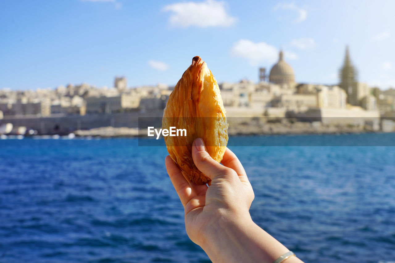 Traditional savoury pastry pastizzi from malta with valletta old town on background, malta island