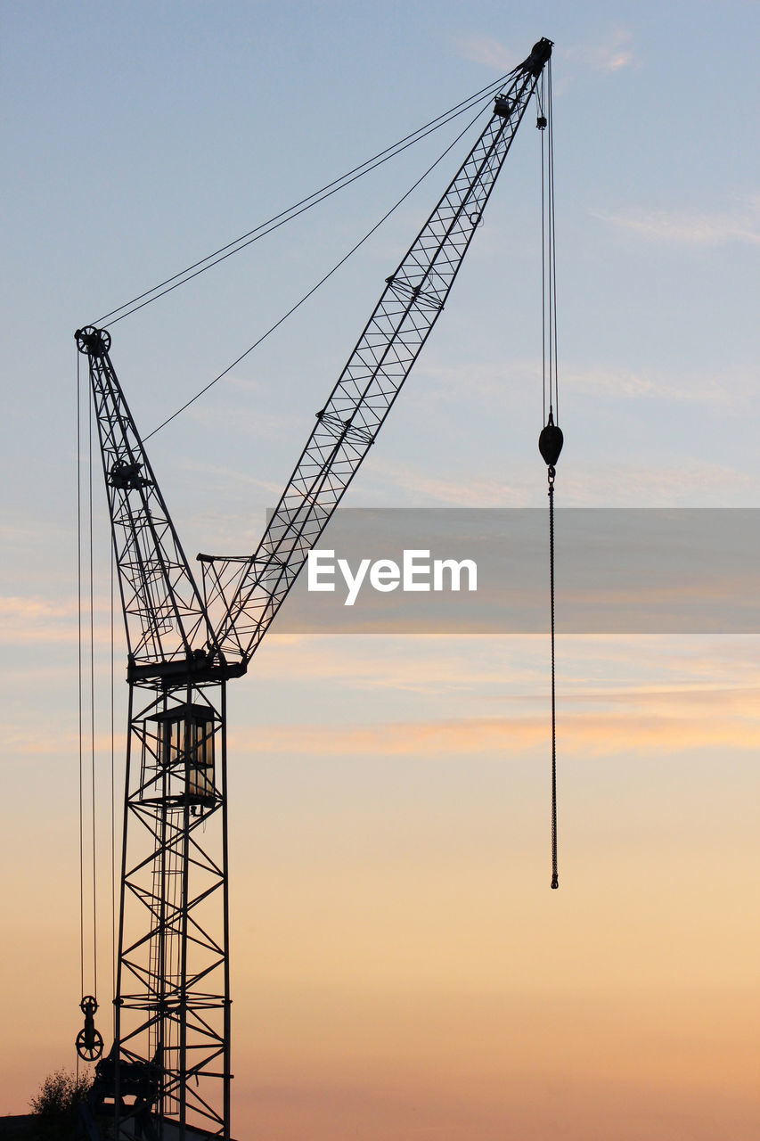LOW ANGLE VIEW OF SILHOUETTE CRANES AGAINST SKY AT SUNSET