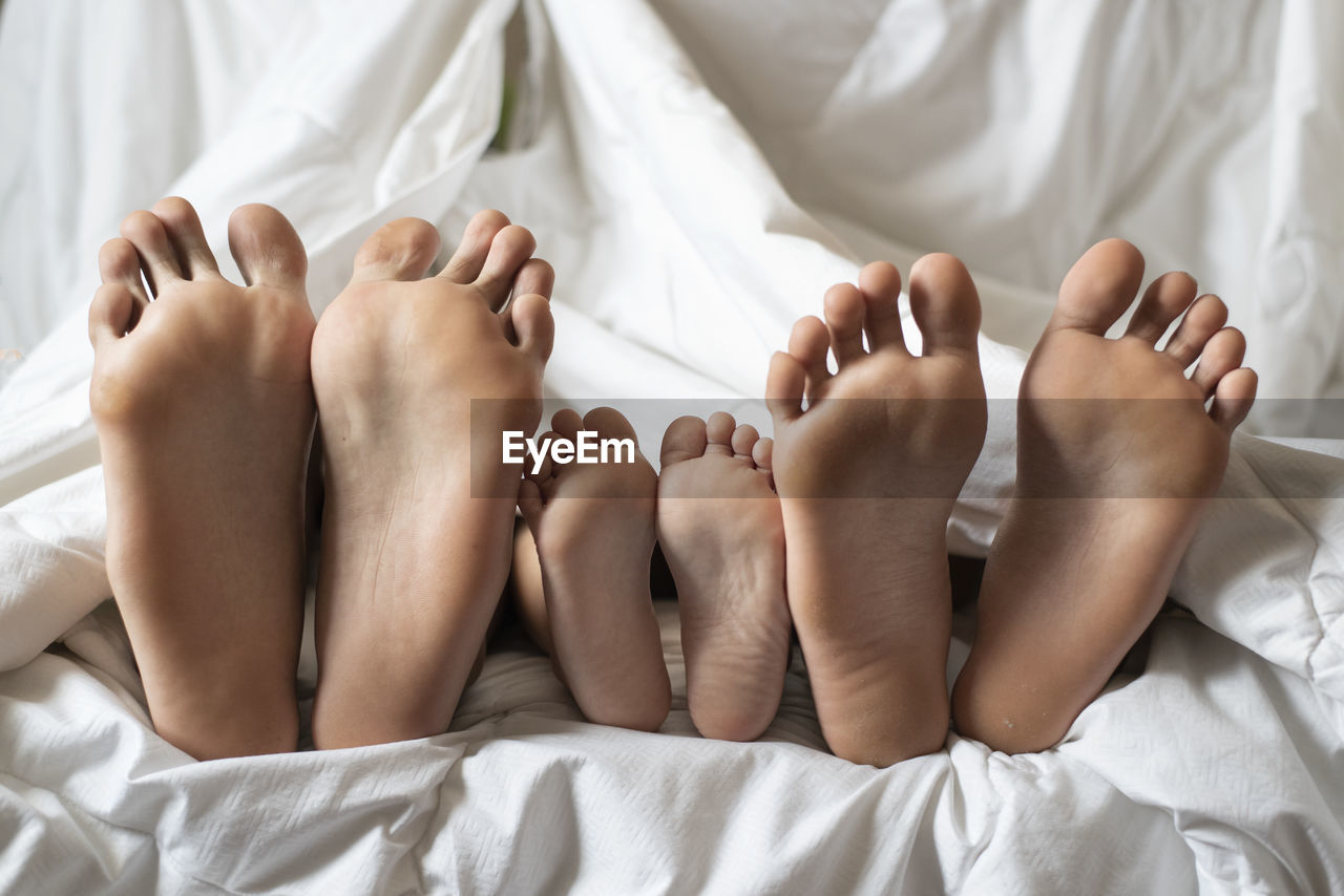 Three siblings showing their bare foot.