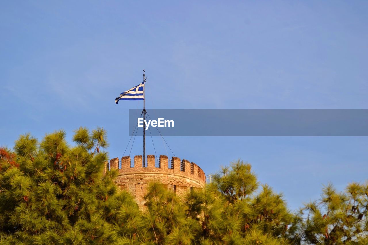 Low angle view of flag against clear blue sky