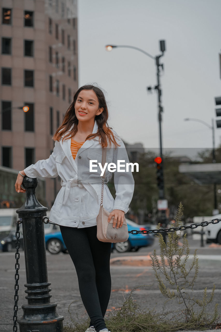 Portrait of smiling young woman standing in city