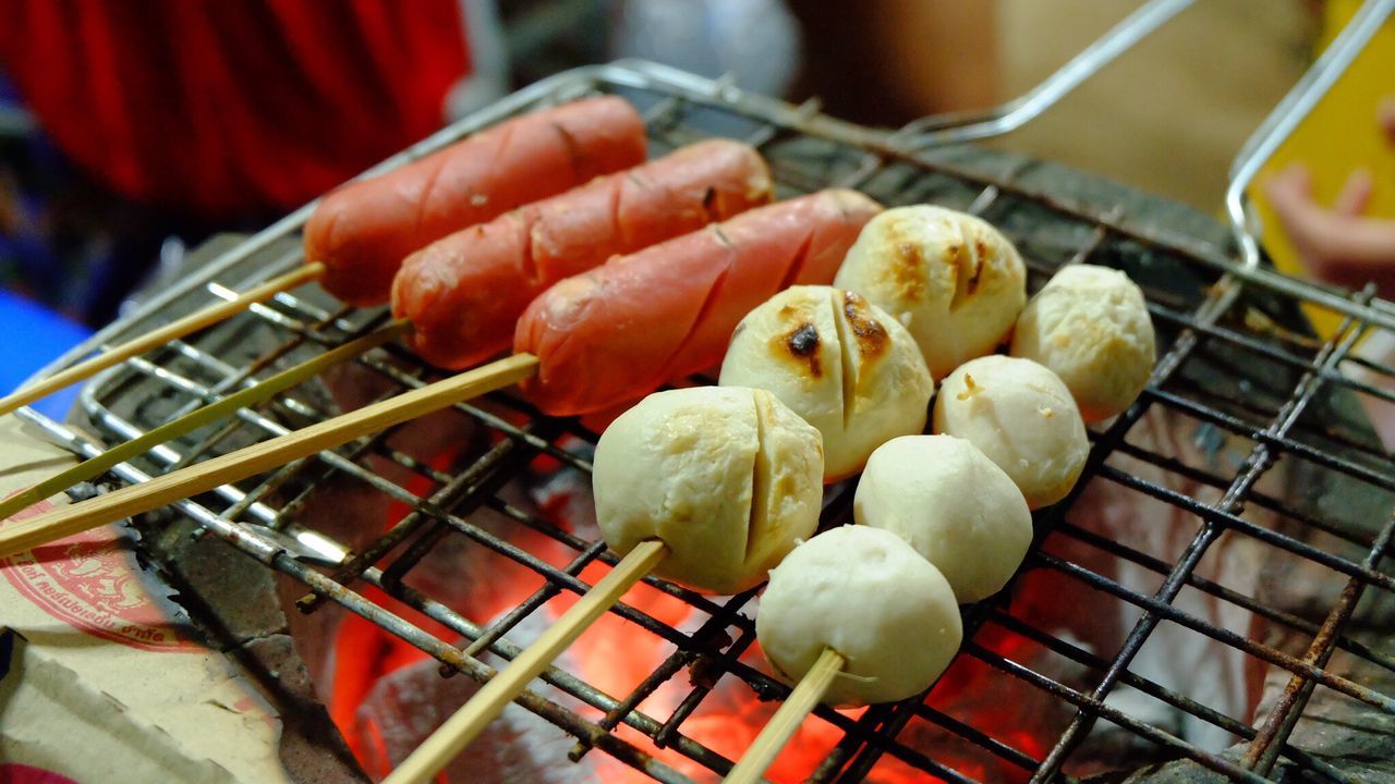 High angle view of fish balls and meatballs cooking on metal grate