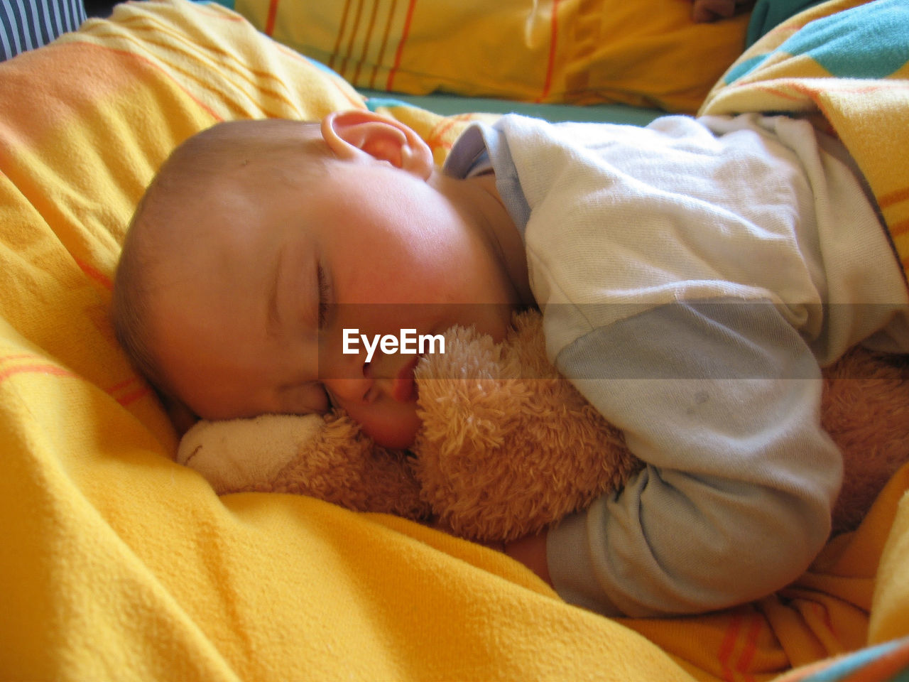 Cute baby sleeping on bed with teddy