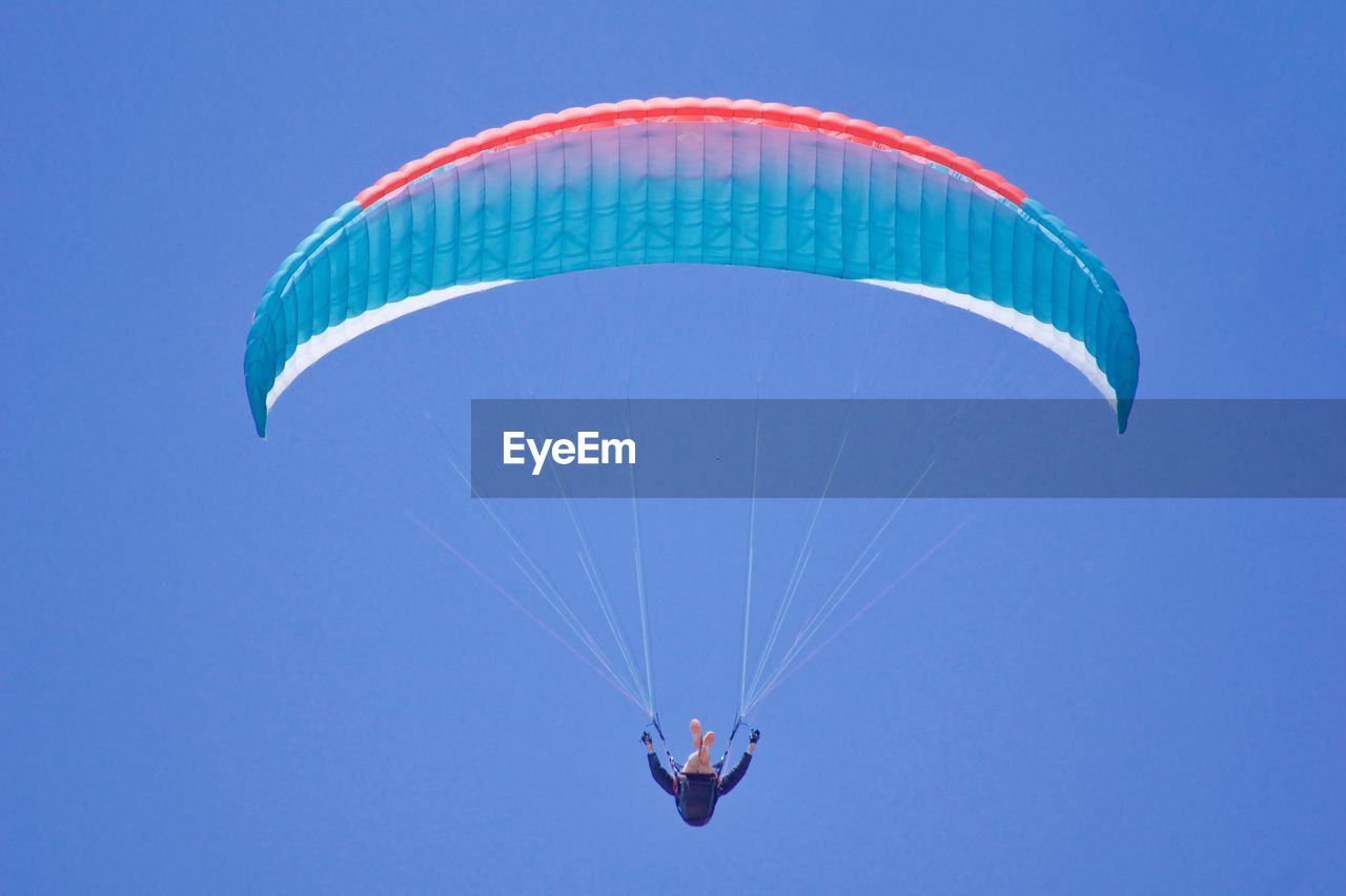 Low angle view of man paragliding against sky 