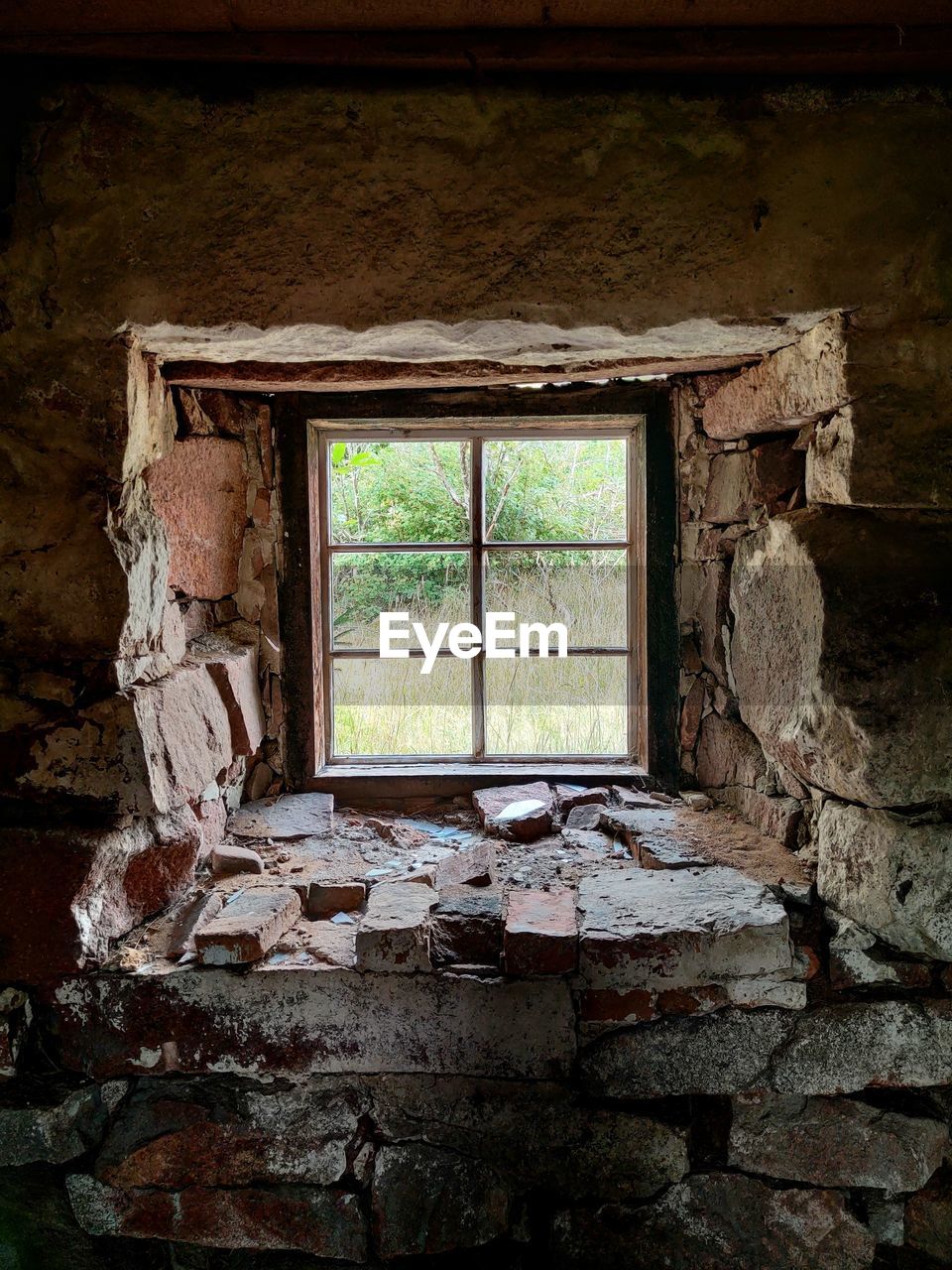 Interior of old, abandoned building, stone framed window with, green nature view