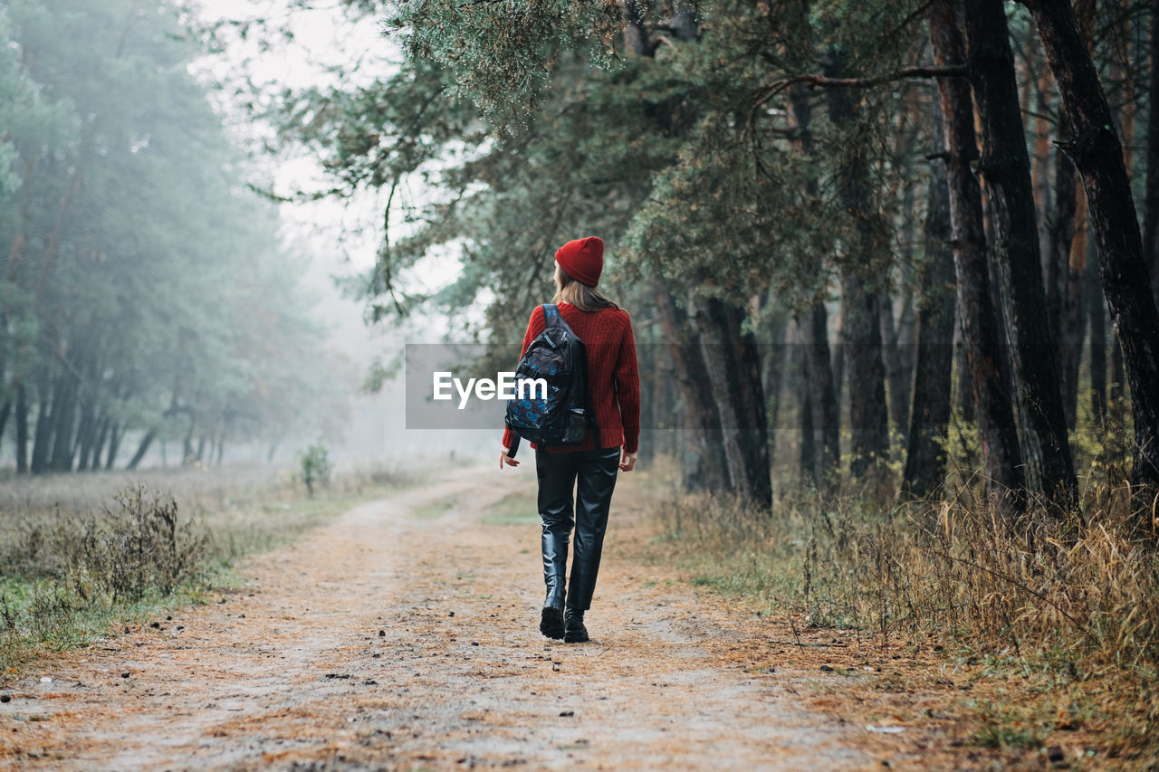 Weekend breaks and getaways in forests. stay close to nature. young woman in red hat and sweater