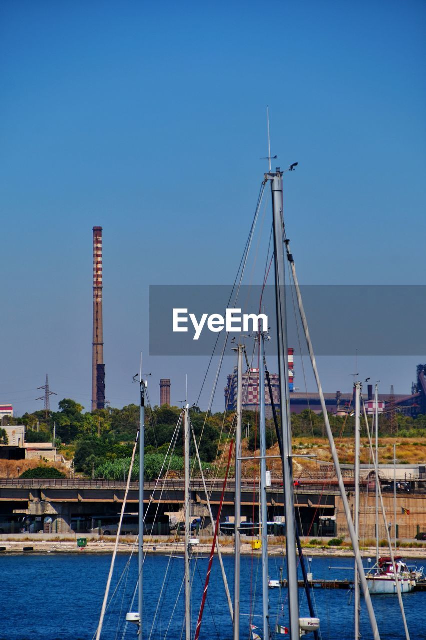 Sailboats in harbor against clear blue sky