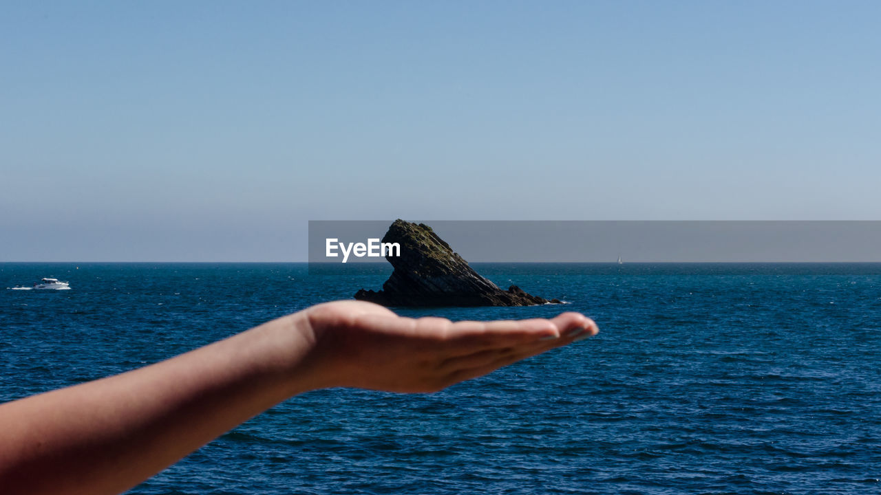 PERSON HOLDING SEA AGAINST CLEAR SKY
