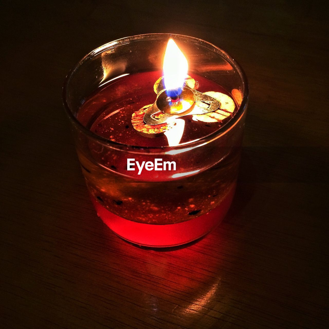 Close-up of lit tea light candle on table in darkroom