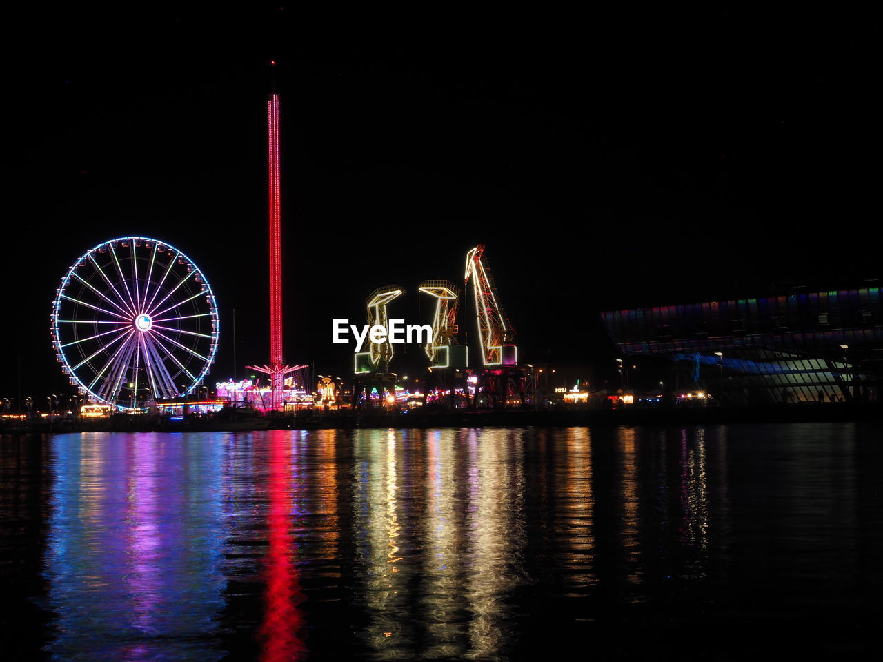 ferris wheel, night, amusement park ride, amusement park, illuminated, arts culture and entertainment, water, architecture, built structure, travel destinations, reflection, city, light, no people, building exterior, sky, transportation, nature, multi colored, outdoors, landmark, nightlife, skyline, waterfront, river, travel, motion, evening