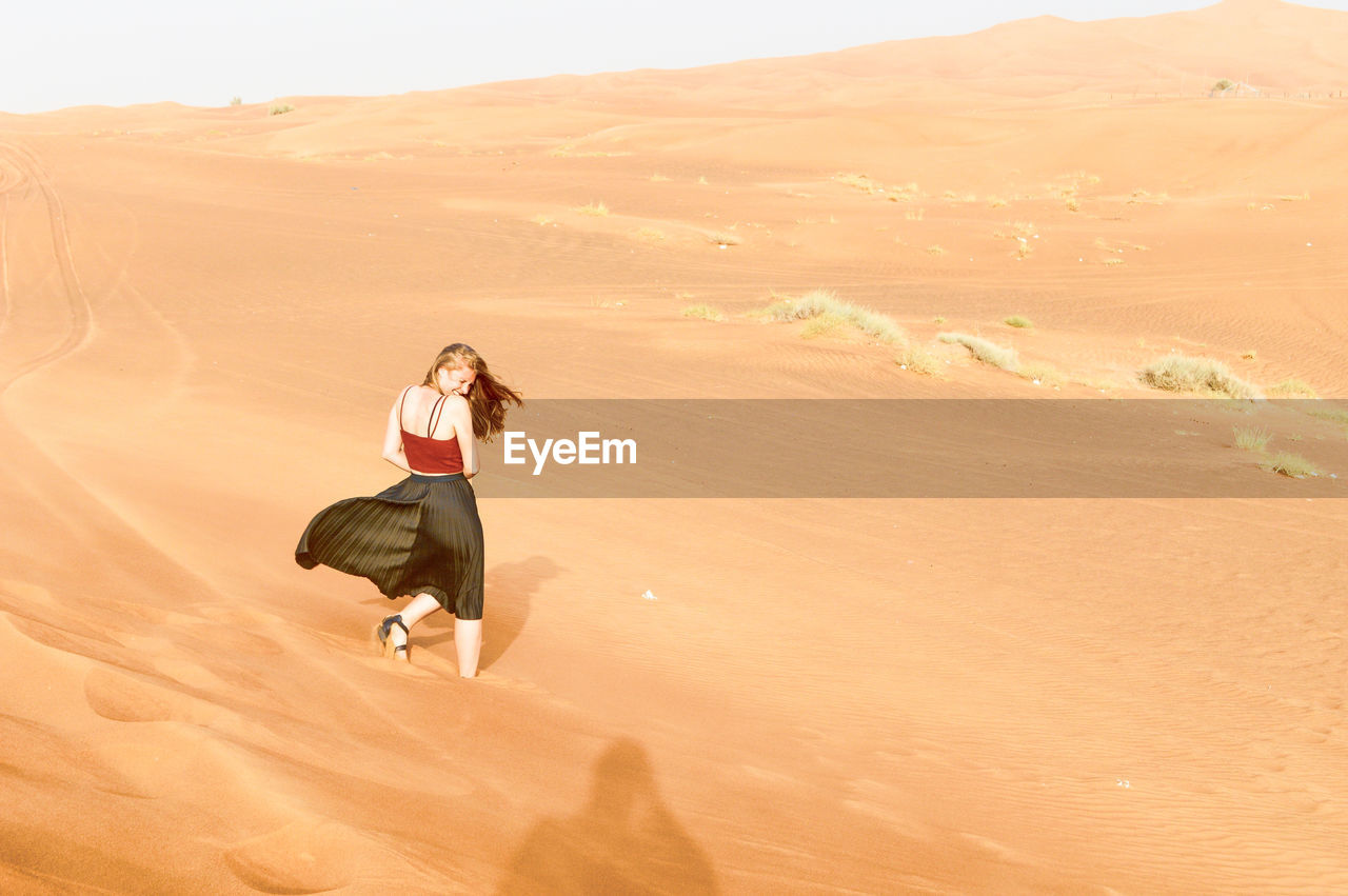 Woman standing on sand dune in desert