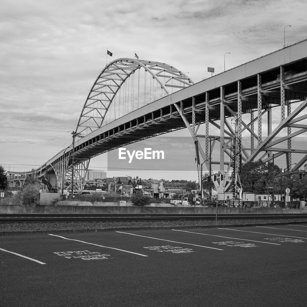 Bridge over railroad tracks in city against sky