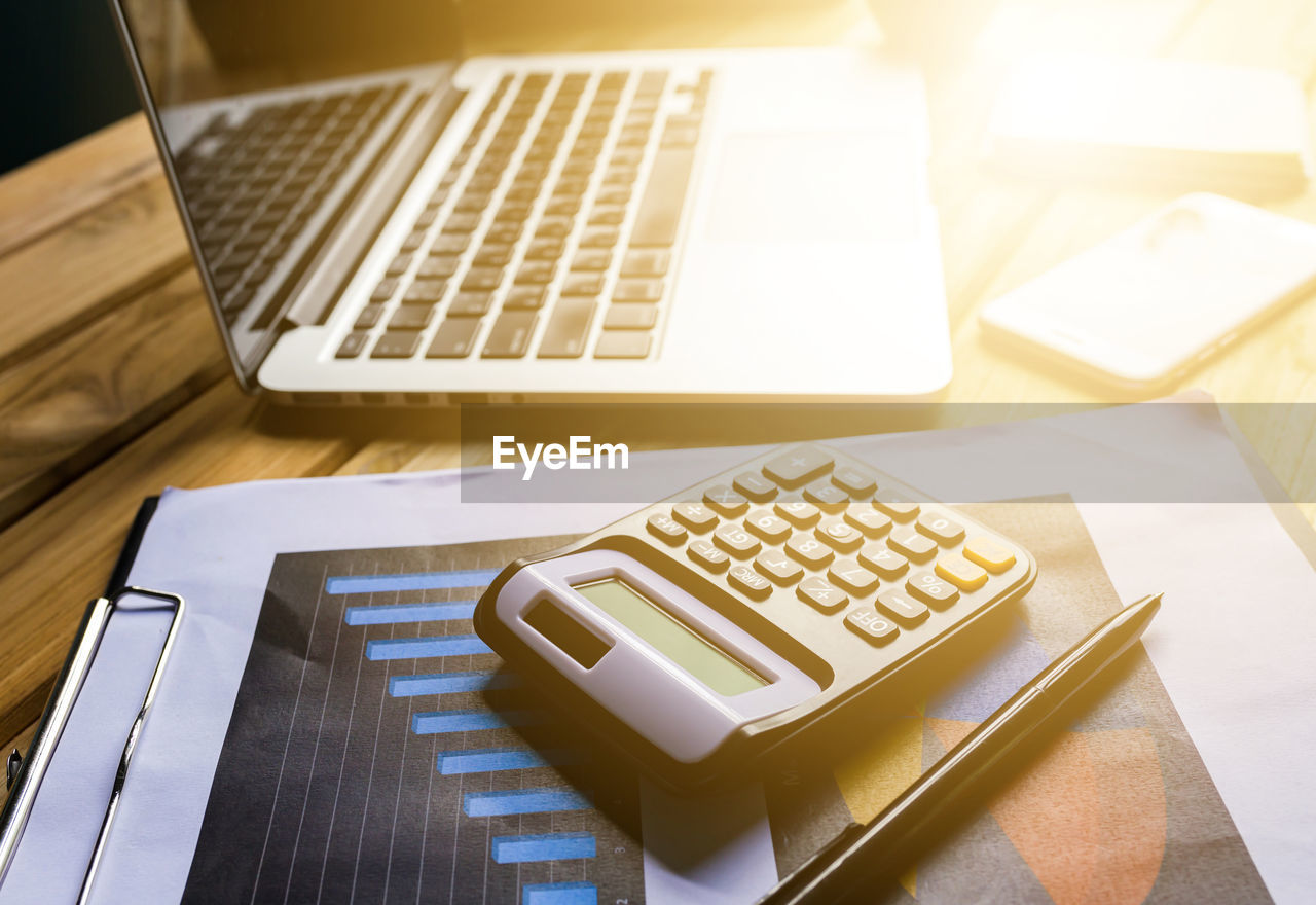 High angle view of laptop with calculator and document on table