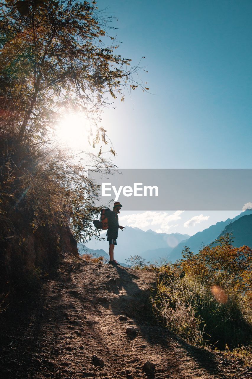 Hiker standing on hill against sky